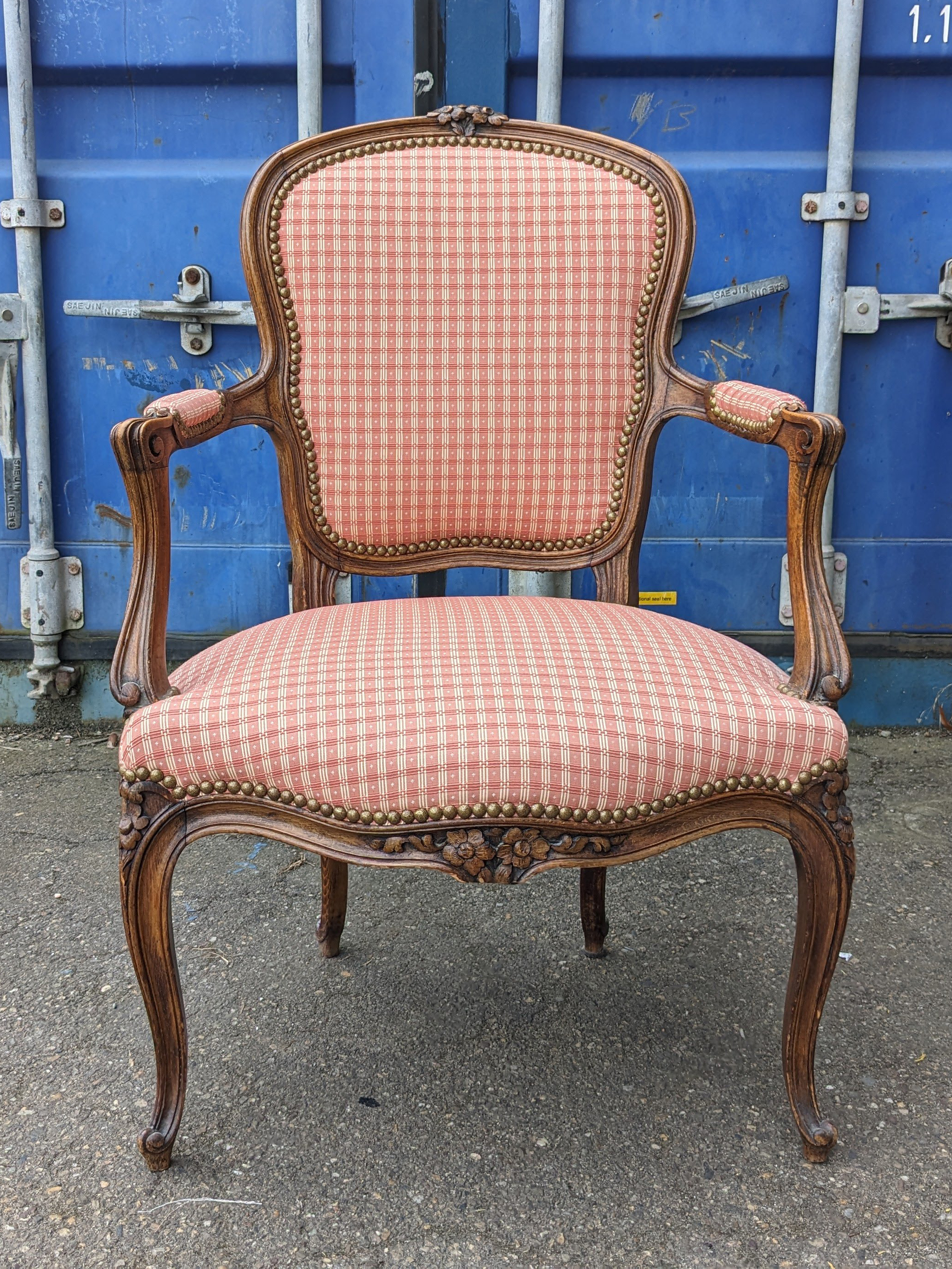 Le fauteuil cabriolet style Louis XV avant réfection, le tissu est à carreaux vichy rouge, le vernis marron foncé!