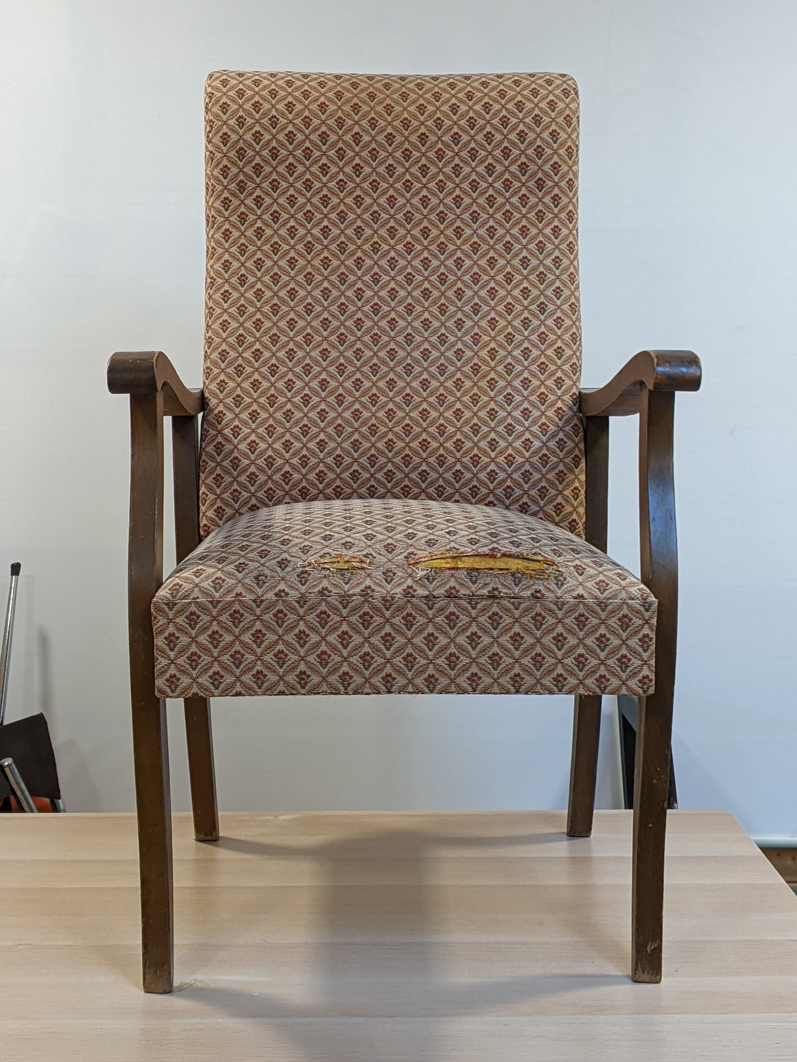 Le fauteuil scandinave avant réfection, le tissu est vieillot et déchiré, le vernis marron foncé!