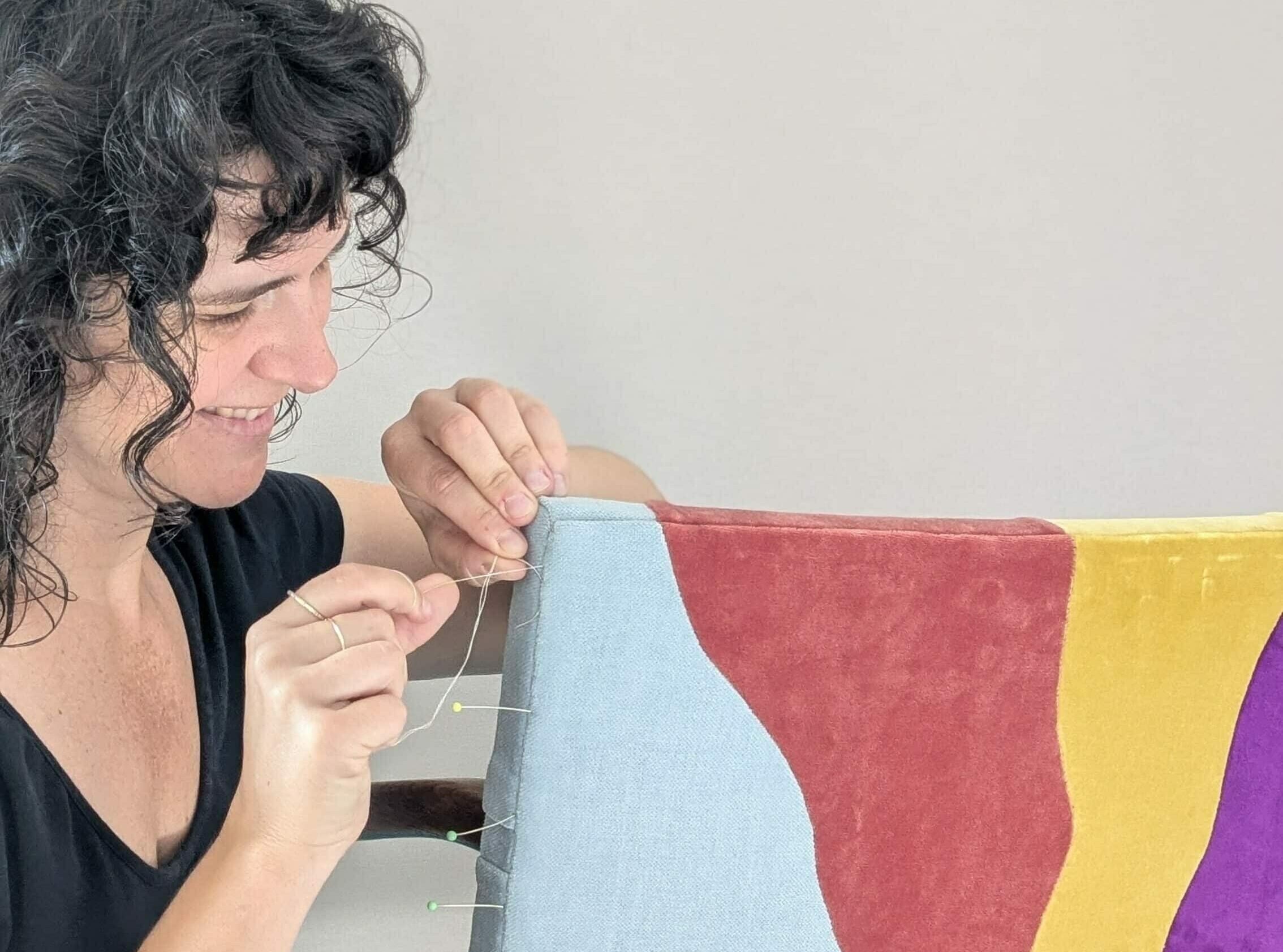 L'artisane Alice Jardillier coud le dossier d'un fauteuil en velours coloré