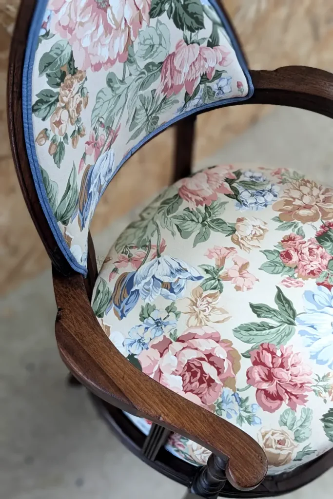 Détail d'un fauteuil recouvert d'un tissu à fleurs avec une finition double corde de chez Houles