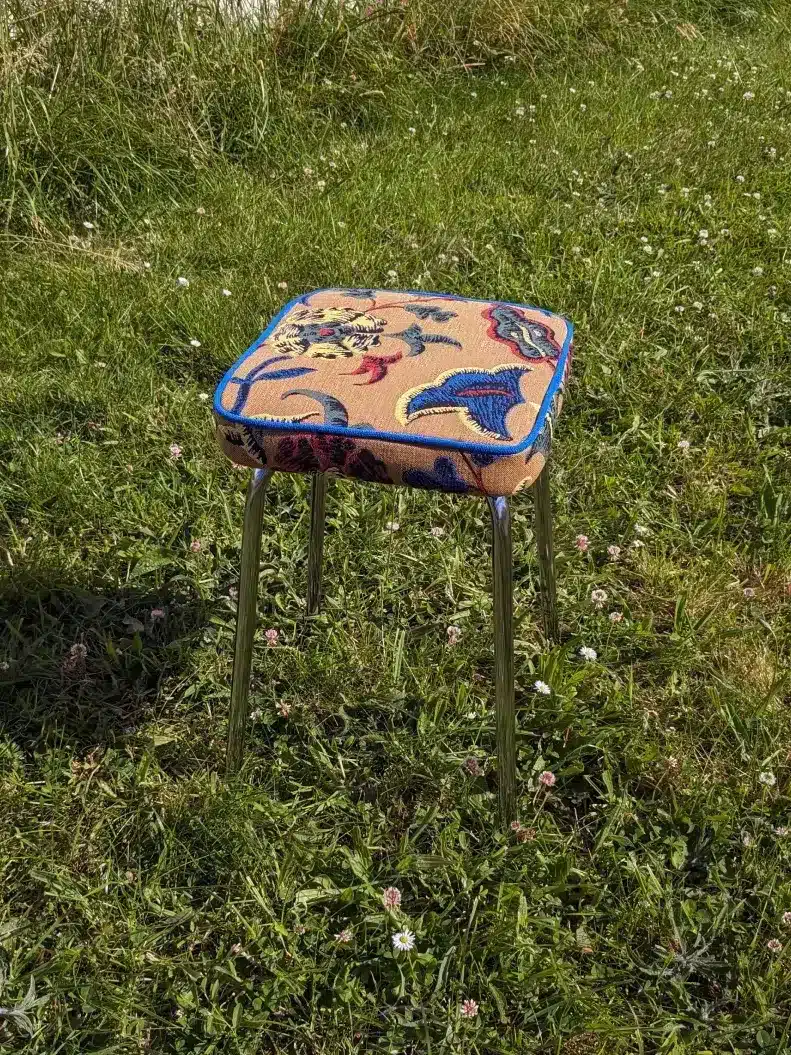 Un ancien tabouret en formica recouvert d'un tissu en jacquard coloré