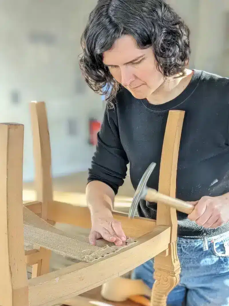 La tapissière Alice Jardillier en train de restaurer un siège en bois